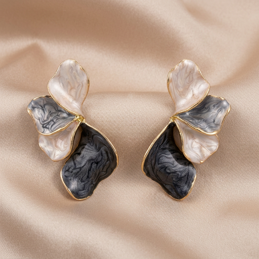 A pair of abstract, organic-shaped earrings with cream, gray, and black marbled enamel sections outlined in gold.