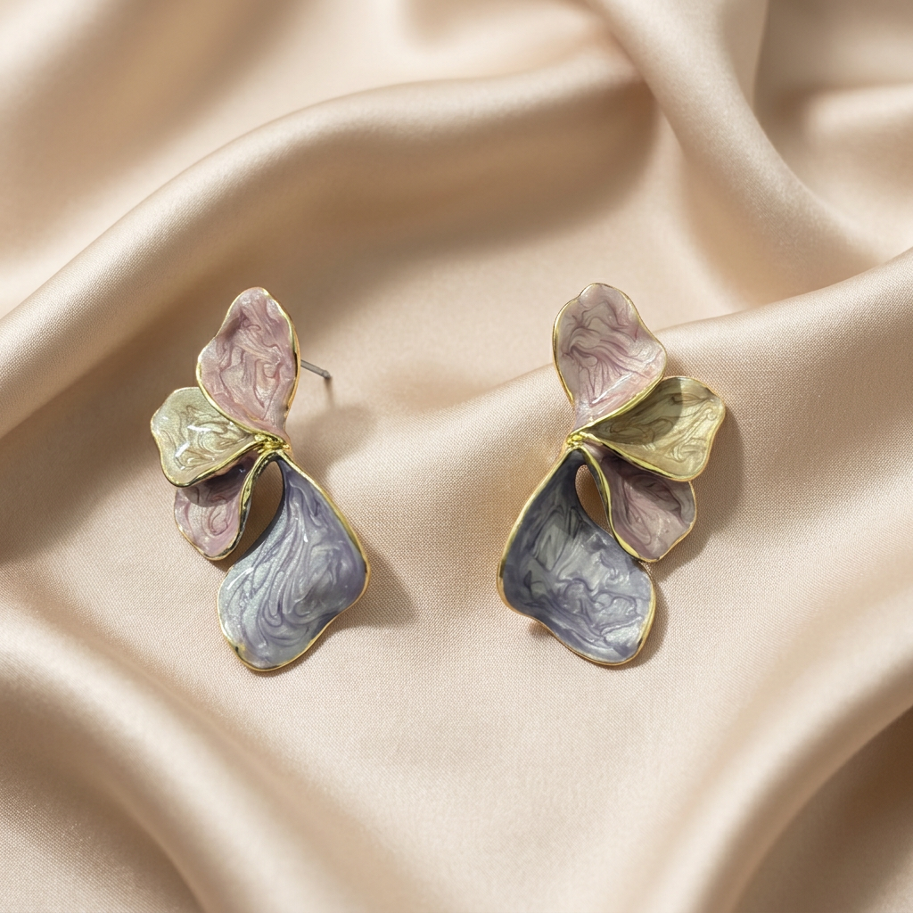 A pair of gold-tone earrings with layered, petal-like shapes in pink, cream, and lavender-gray enamel.