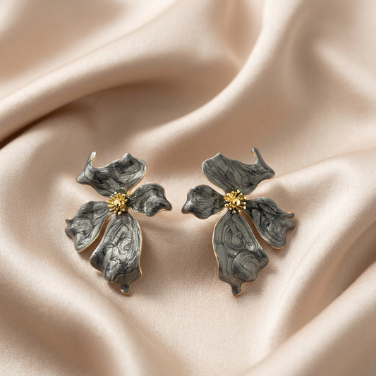 A pair of flower-shaped earrings with marbled gray petals and gold-tone edges.