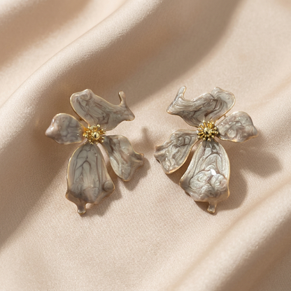 A pair of vintage-style flower-shaped earrings with marbled off-white petals and gold centers.