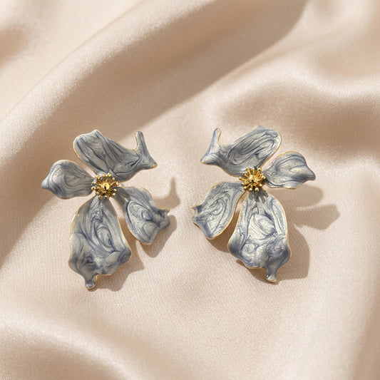 A pair of flower-shaped earrings with marbled light gray petals and gold-tone centers.