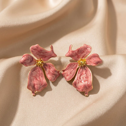 A pair of pink dogwood flower stud earrings with gold centers.