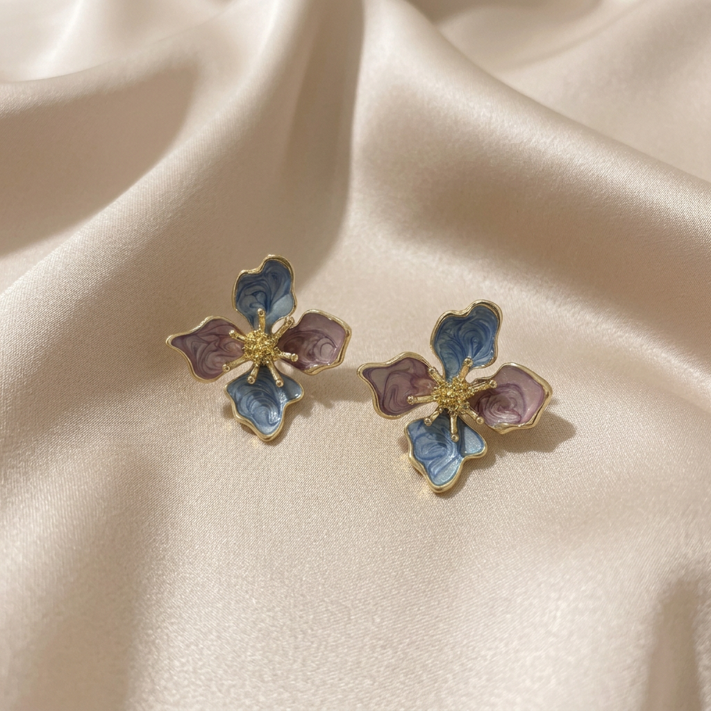 A pair of vintage-style floral stud earrings with gold-plated metal borders, light blue enamel petals, and mauve-pink enamel centers.